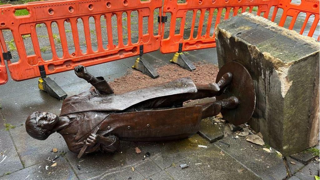 The Victoria Wood statue in Bury, knocked over and covered in debris