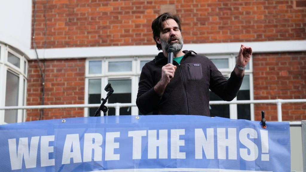 Rob Delaney with a We Are The NHS! banner