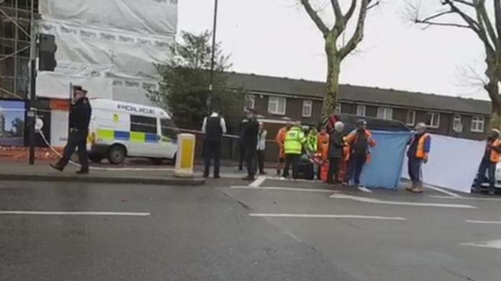 Police van and officers in high viz outside a construction site, as seen from the other side of the road