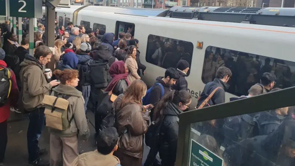 A crowded train platform, with lots of people trying to board a train