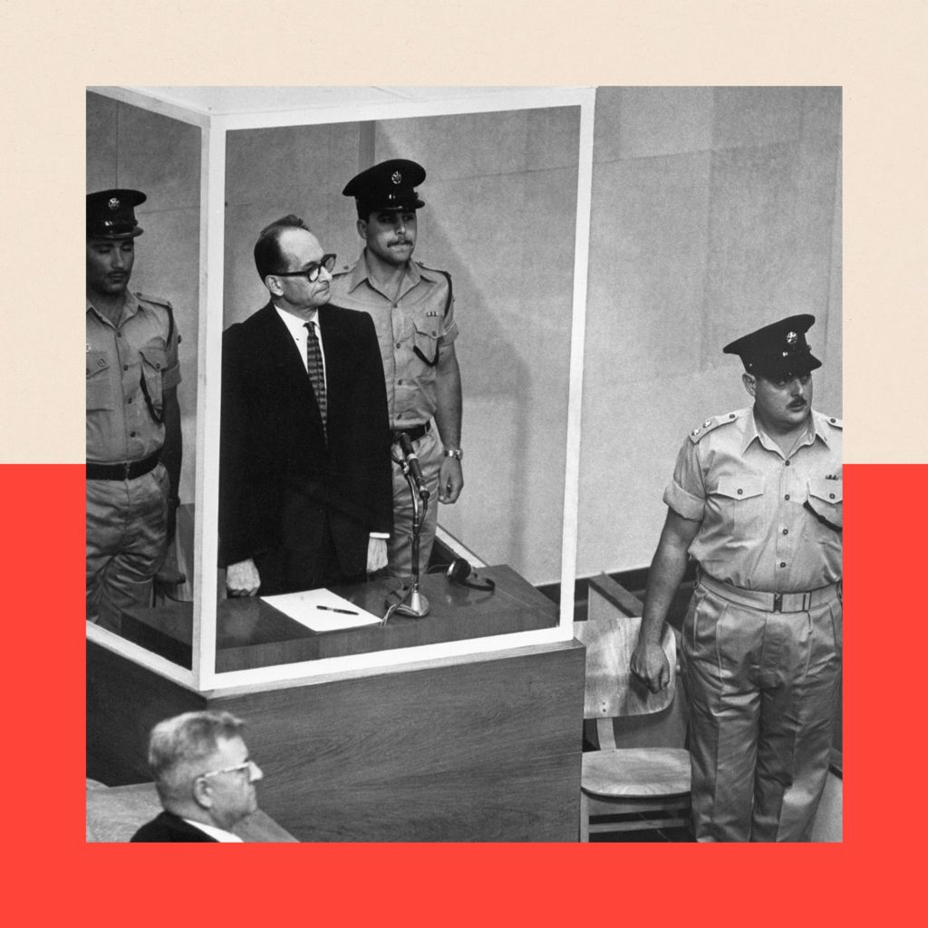 Adolf Eichmann stands in his bullet-proof glass cage to hear Israel's Supreme Court unanimously reject an appeal against his death sentence. With him are two armed guards.