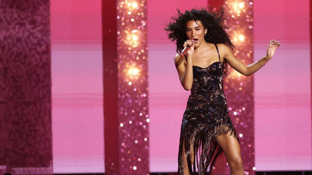 Olivia Dean performing at the Brits for fans while wearing a black dress