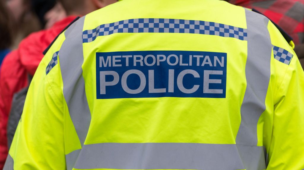 Image of the back of a police officer wearing a jacket which reads: "Metropolitan Police". 