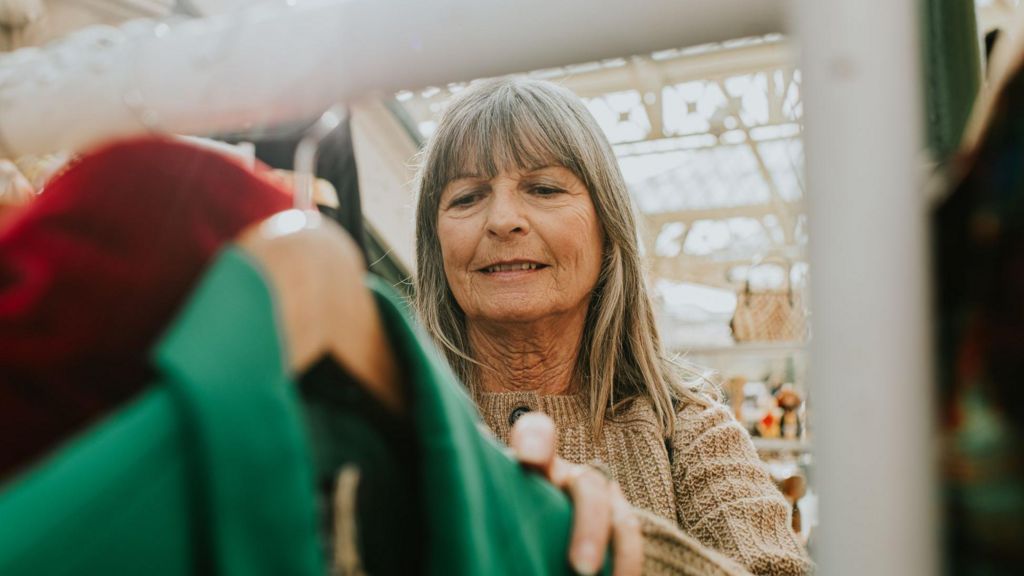 Woman looks at a rack of clothes in a market.