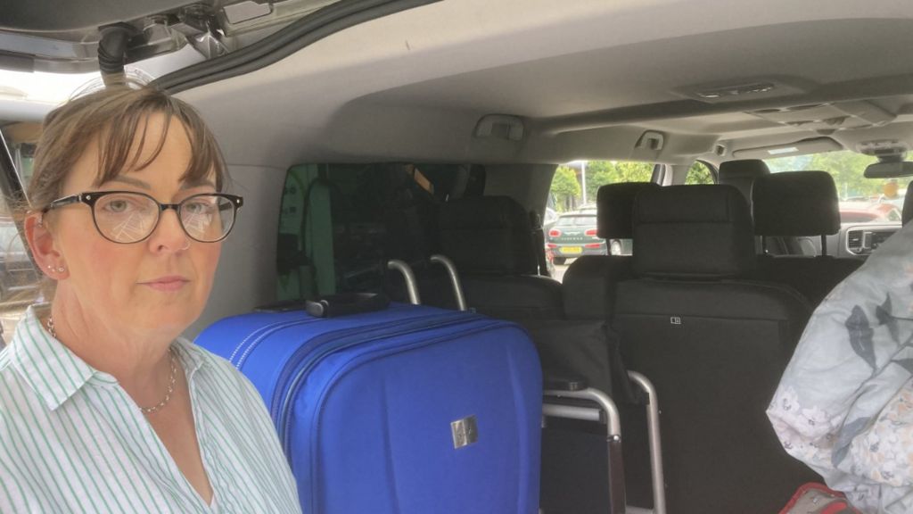 Rhoda Woodburn beside belongings in back of vehicle in Newtownards