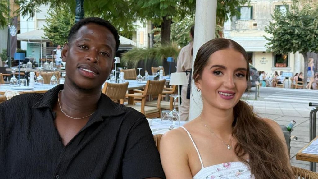 Tommy and Amy sit in a town square with chairs and tables around them