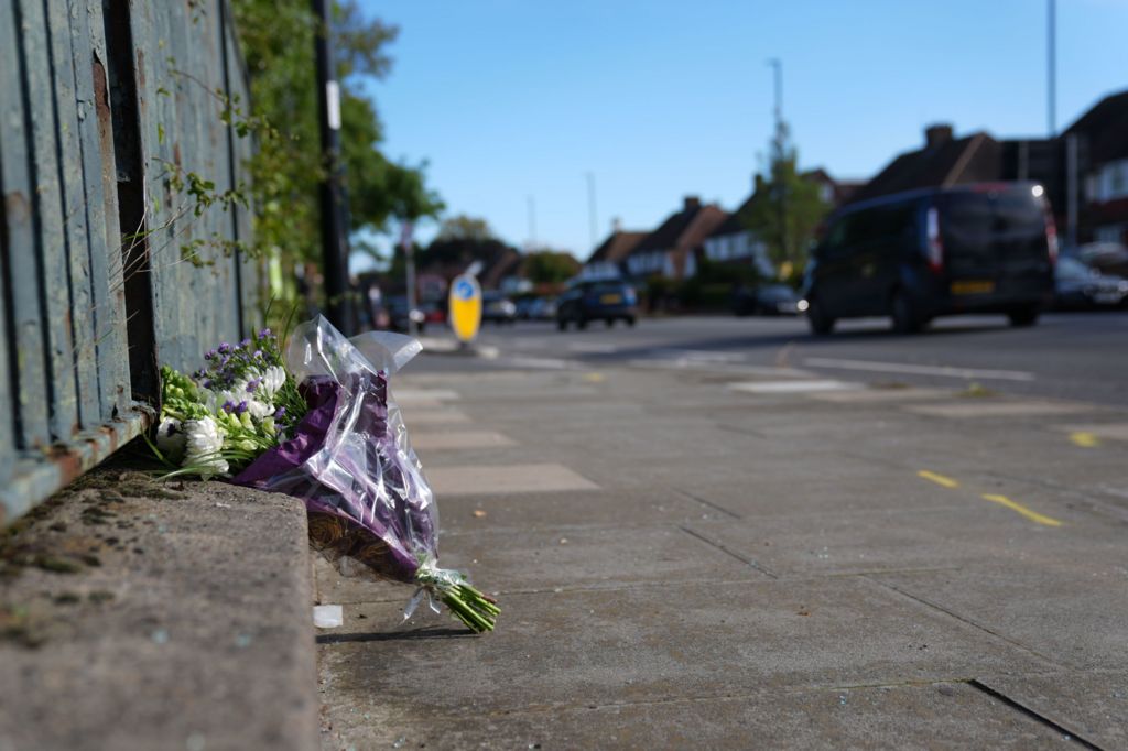 White and purple flowers in a bouquet at roadside. Vehicles are in the background
