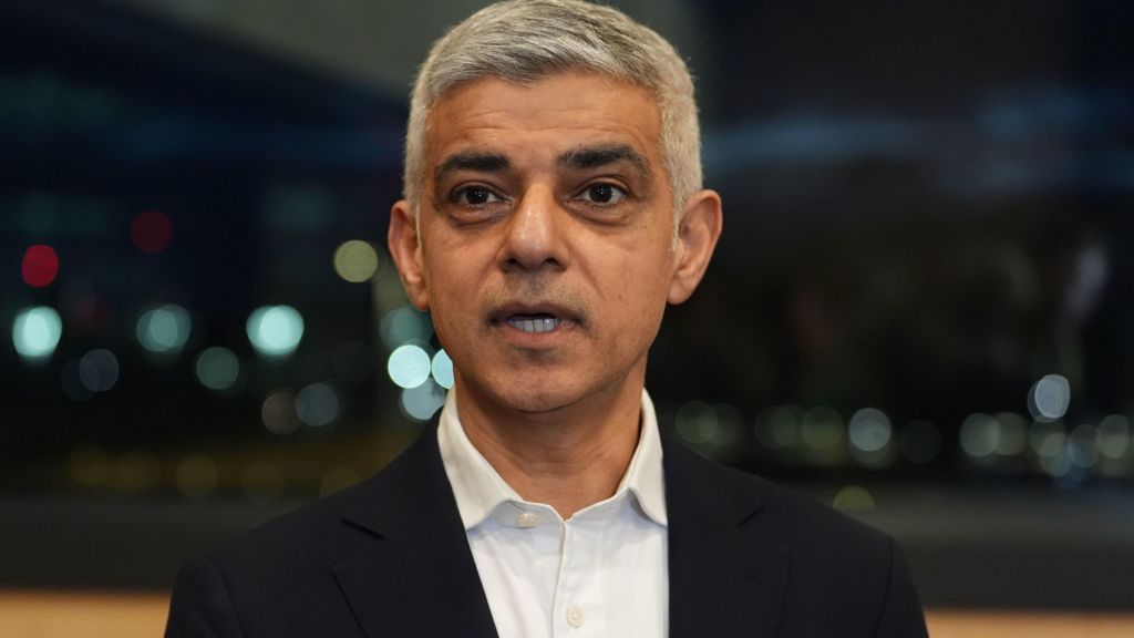 Sadiq Khan, wearing suit jacket and white shirt, looks at the camera