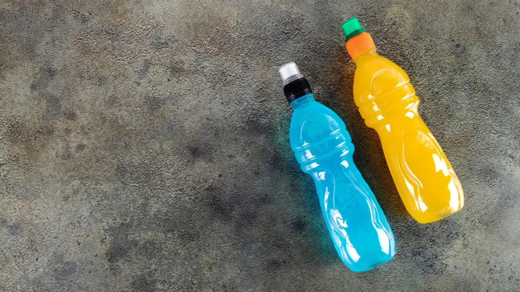 Blue bottle of isotonic drink, L-carnitine, sports energy drink on gray background. Bottle of fitness drink.
