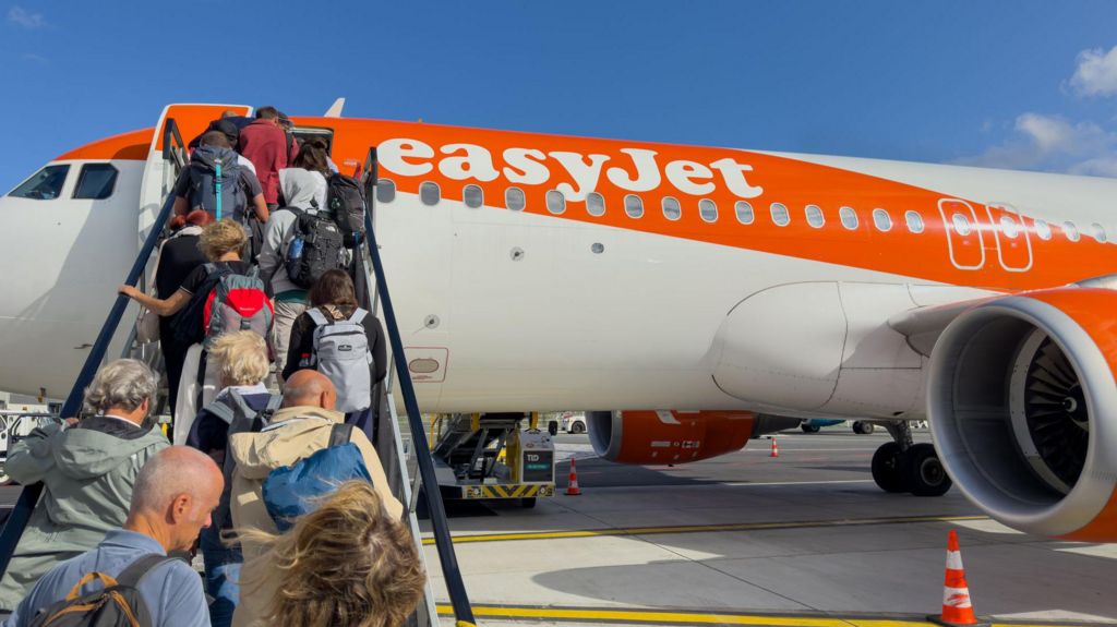 Passengers walking up a set of stairs to board an EasyJet plane
