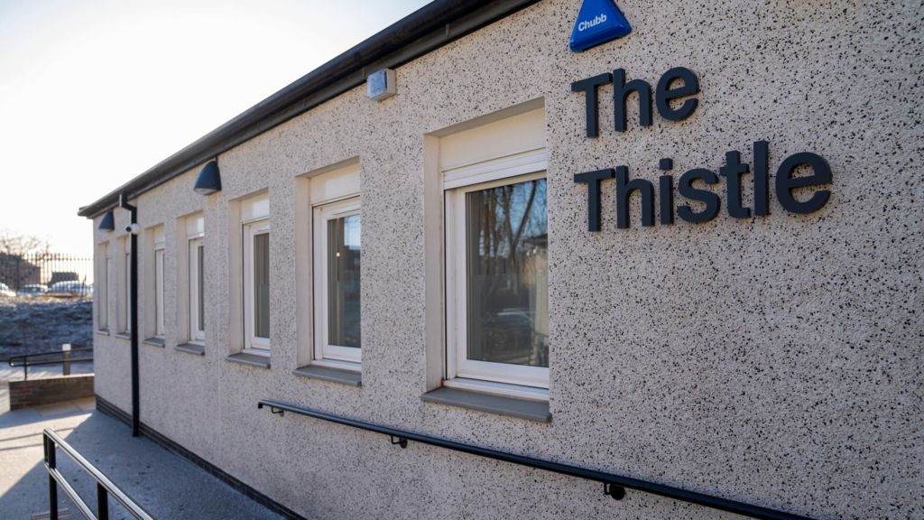 The outside of the grey pebble dash building, with the words The Thistle on the side.