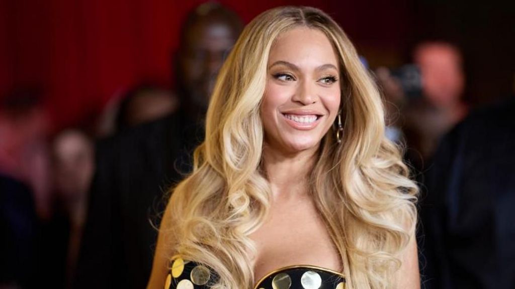 Beyonce has long blonde hair and a strapless gold and black spotted dress