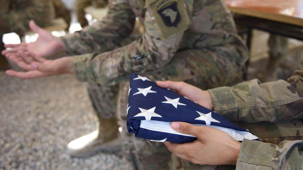 Американский солдат держит национальный флаг перед церемонией передачи в лагере Лезернек в Лашкар-Гахе в афганской провинции Гильменд