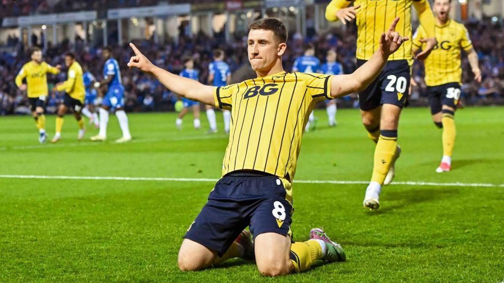 Oxford United midfielder Cameron Brannagan slides on his knees 