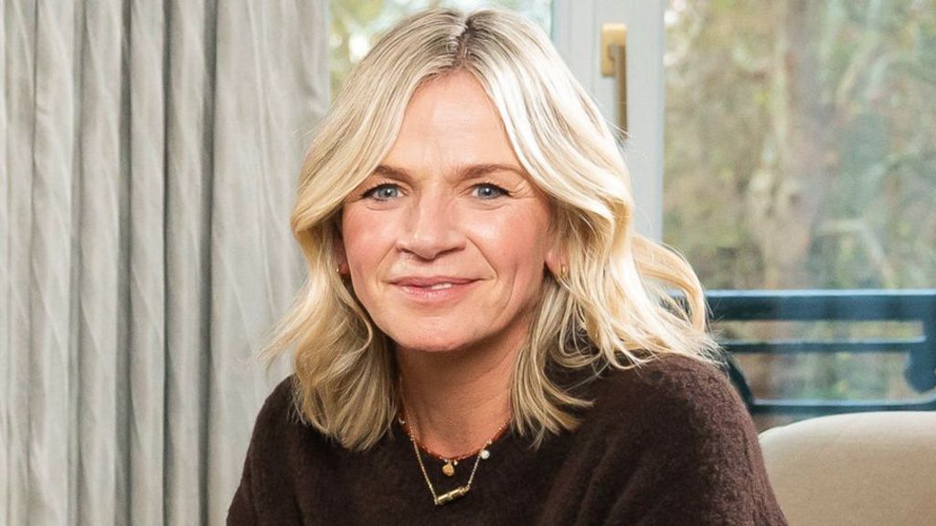 Zoe Ball pictured sitting on an armchair, wearing a brown jumper
