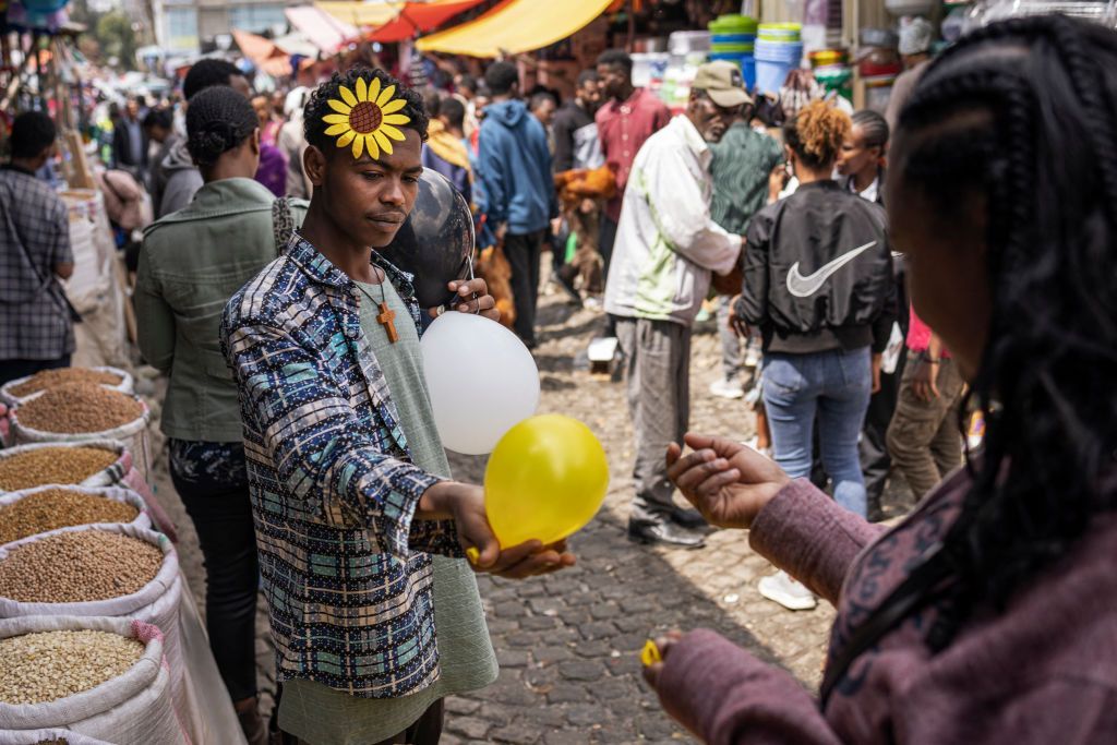 A street vendor with a flower ornament known as 'Adey Abeba' in his air sells a balloon.