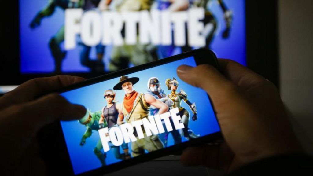 Hands holding a mobile phone with the Fortnite logo on it