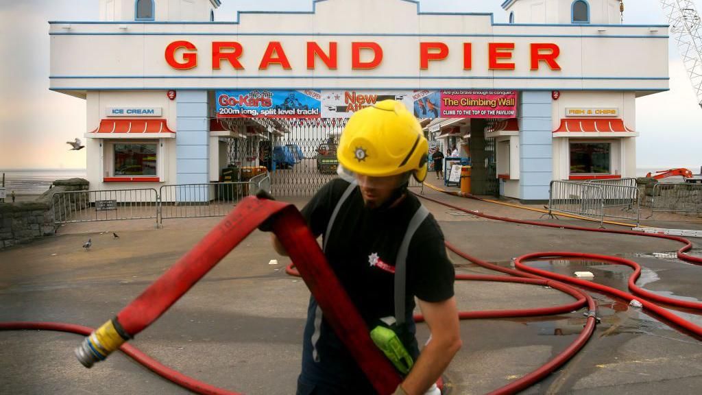A fireman is seen at work in front of the burnt out Weston Super-Mare pier, Somerset on July 28, 2008