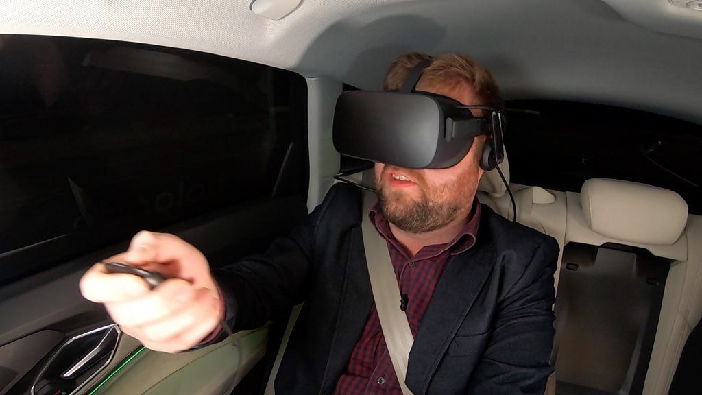 Dave Lee in the back of an Audi, wearing VR