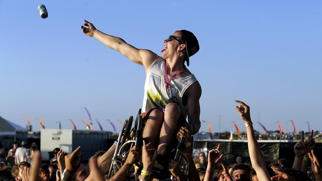 A music fan in a wheelchair is held aloft by the audience