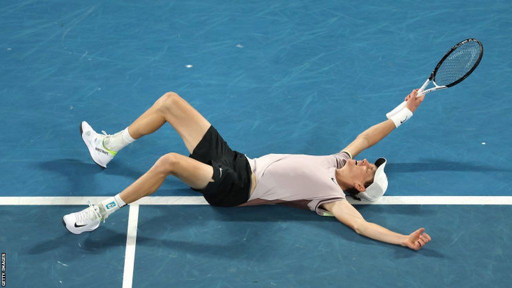 Jannik Sinner falls to the court after winning the Australian Open title
