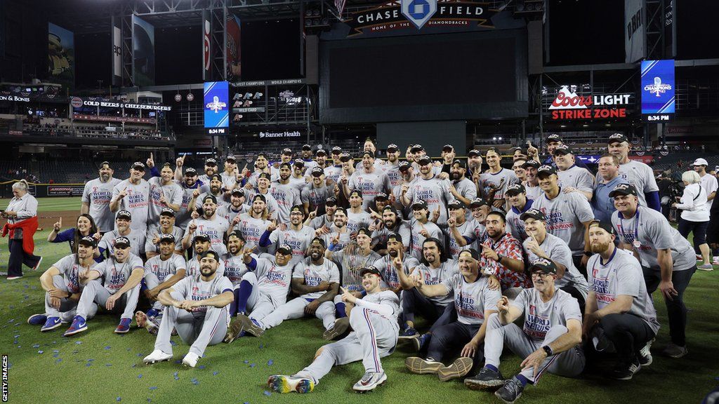 The Texas Rangers players sit on the outfield after winning the World Series