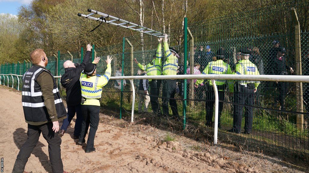 Police confiscate ladders from protesters attempting to climb over security fencing to access the Grand National racecourse at Aintree