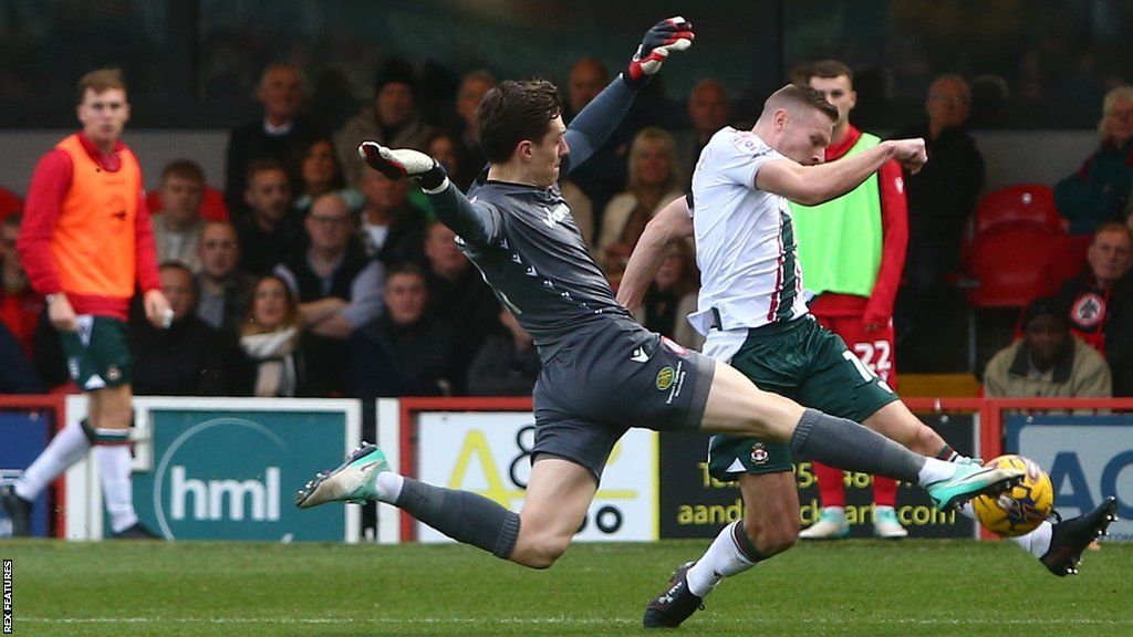 Accrington's Jon McCracken blocks a goal attempt by Paul Mullin