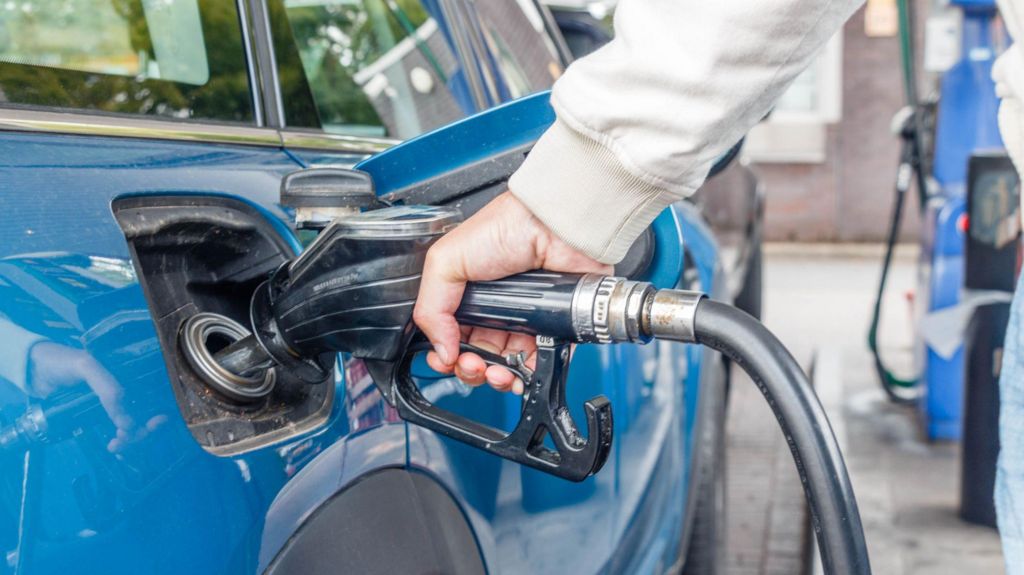 A person filling up their car at a petrol station.