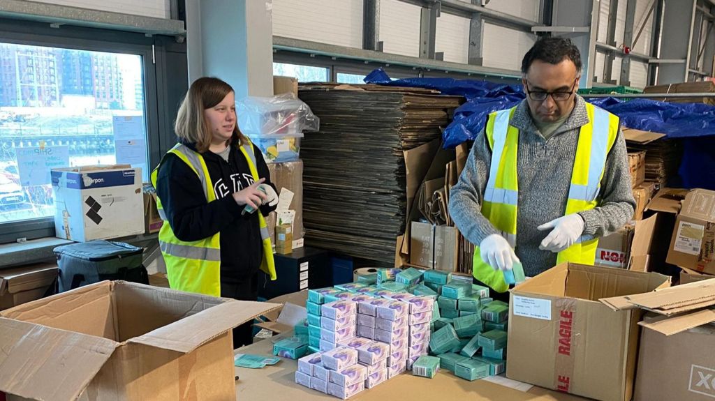 Taylor and Jentital packing soap in a warehouse in London. They are both wearing high-vis jackets 