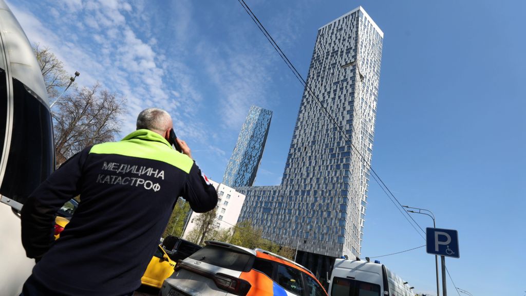 An emergency doctor looks at a damaged high-rise building