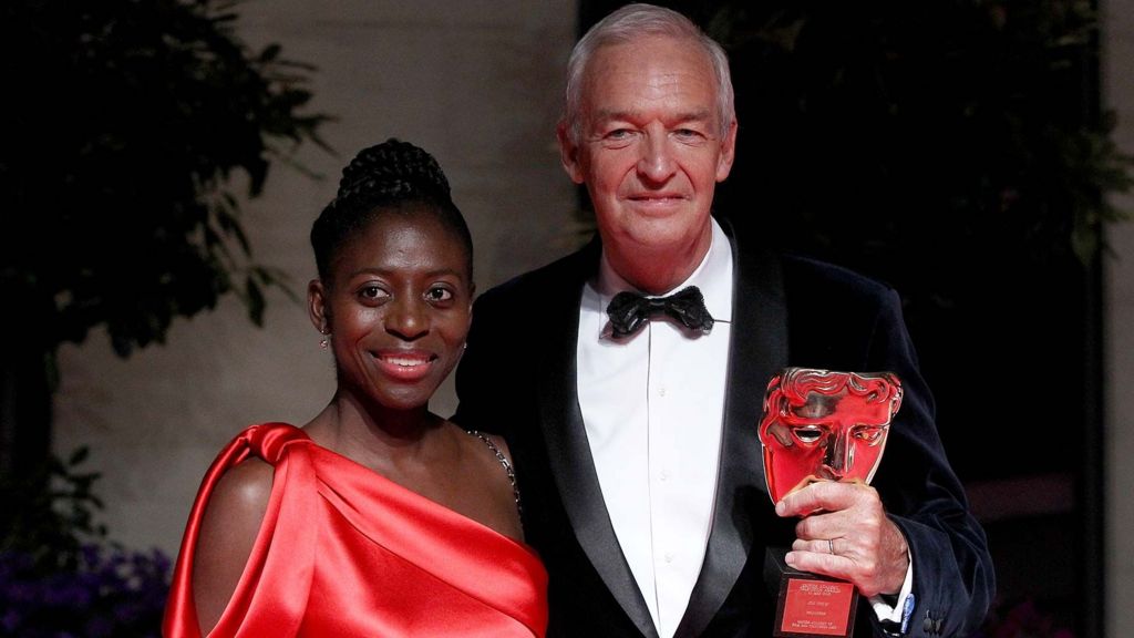 precious Lunga in a red dress and Jon Snow holding a bafta