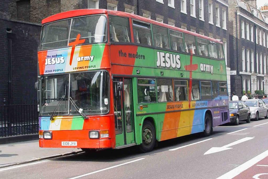 A brightly-coloured Jesus Army bus parked outside a row of terraced houses in London