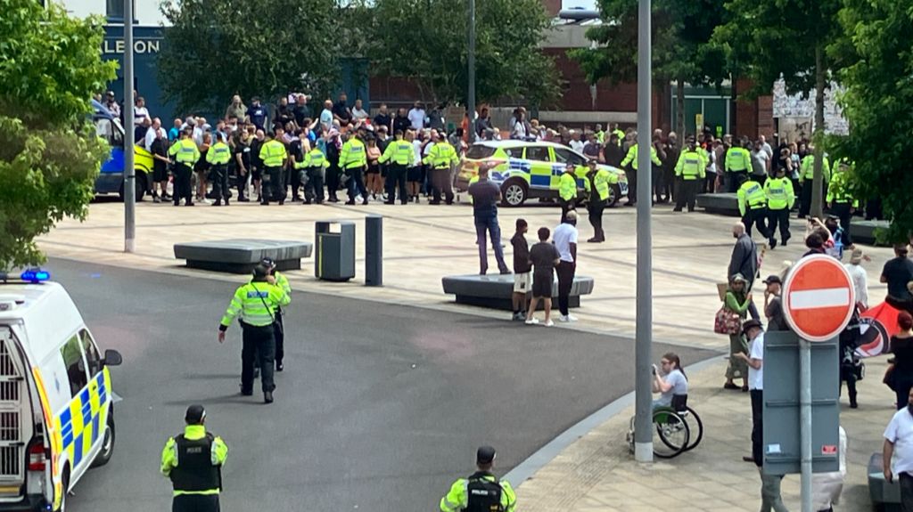 A line of police officers stand between protestors