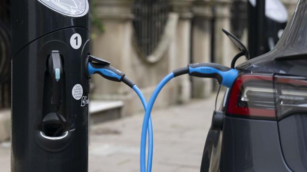 A car charging at an charge point in London. A big blue cable connects the two.