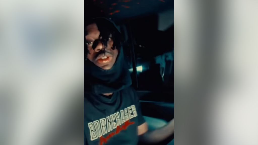 Boakye looks to camera with a hood over his head part of his lower face