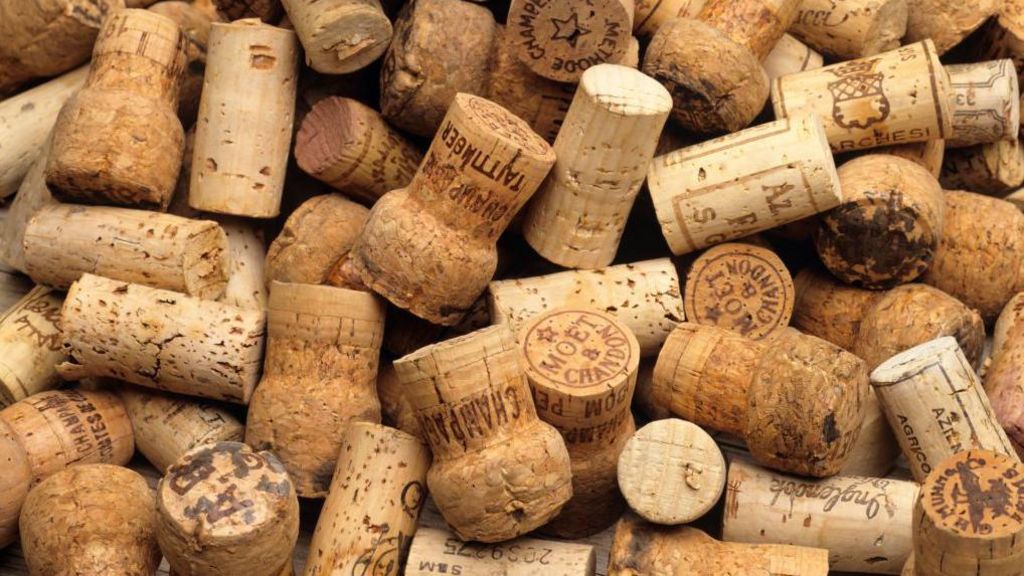 A pile of corks from champagne and other wines. Some of the writing on them states Tattinger, Moet & Chandon and some have serial numbers on them too.