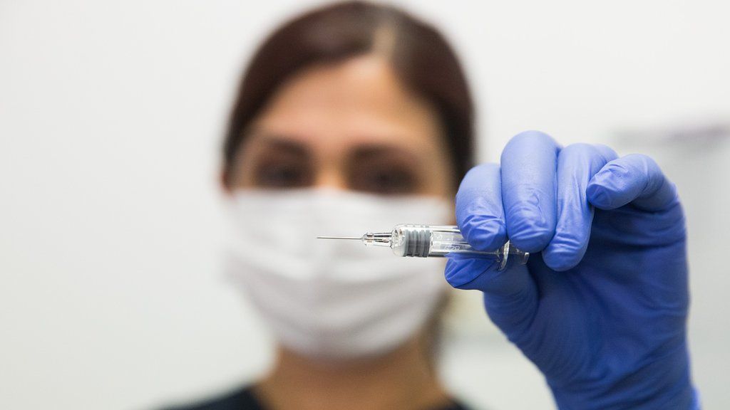 A nurse holds an ampoule to be used on a volunteer who is vaccinated with a coronavirus vaccine test