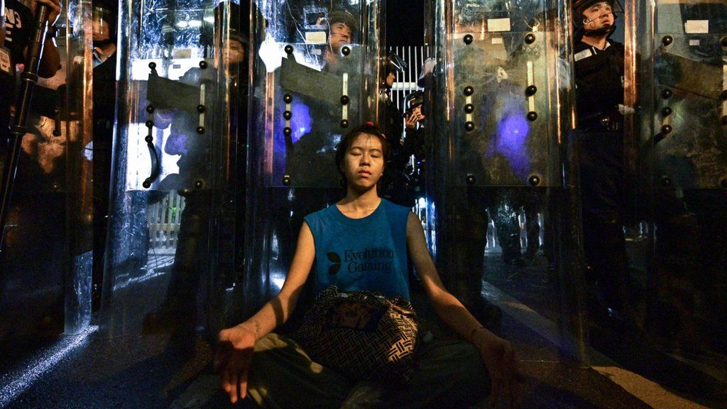 A female protester meditates in front of riot police outside the government headquarters in Hong Kong