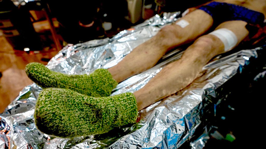 The wounded soldier's feet are kept warm in hand-knitted woolen socks