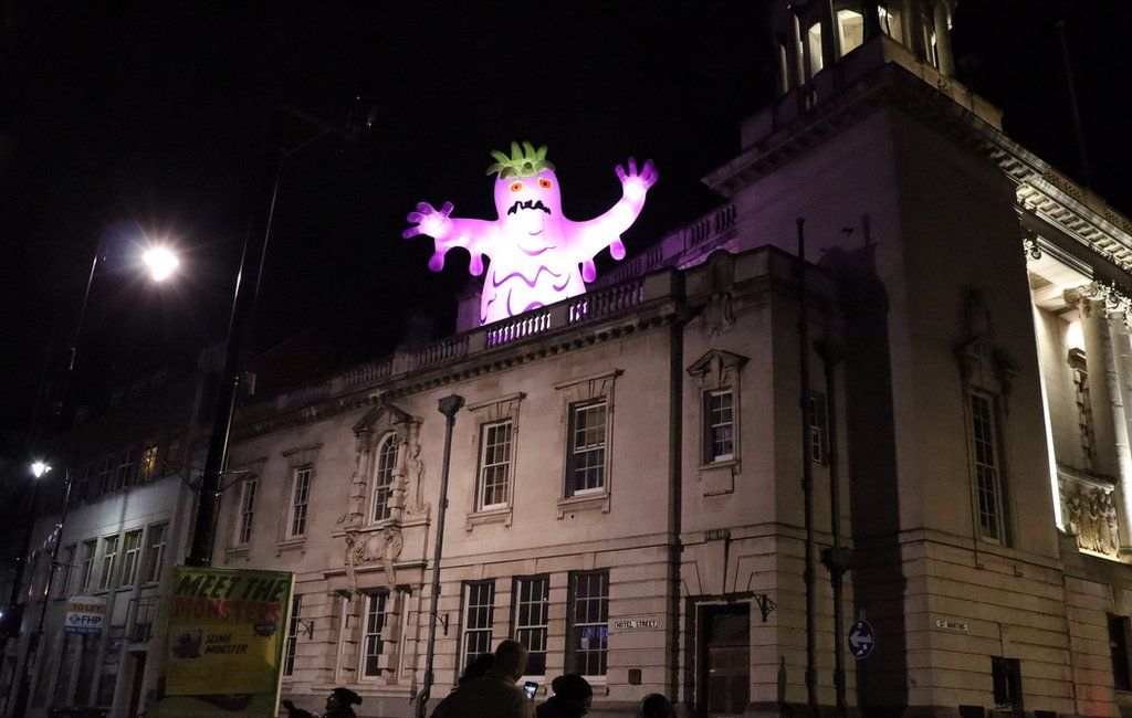 A purple monster at the top of a building