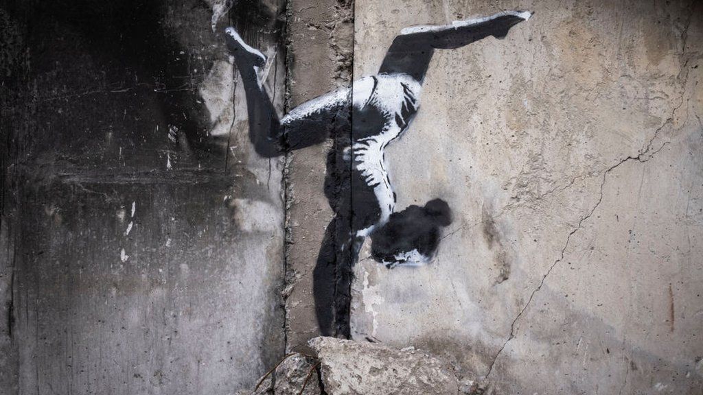 Graffiti of a gymnast doing a handstand painted on a destroyed building in Borodyanka