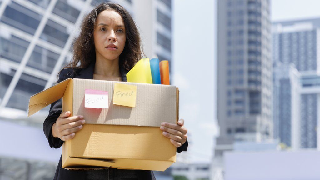 A stock image of a fired woman carrying her possessions in a box