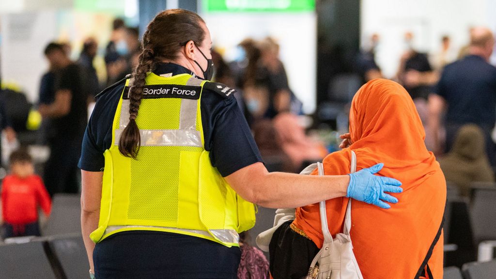 UK border force staff member assists a refugee at Heathrow Airport in August 2021