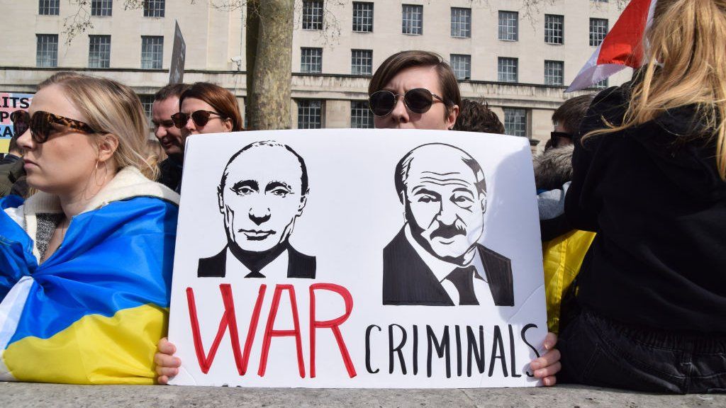 A protester holds up a sign branding Putin and Lukashenko as war criminals during a demonstration in London against the war in Ukraine