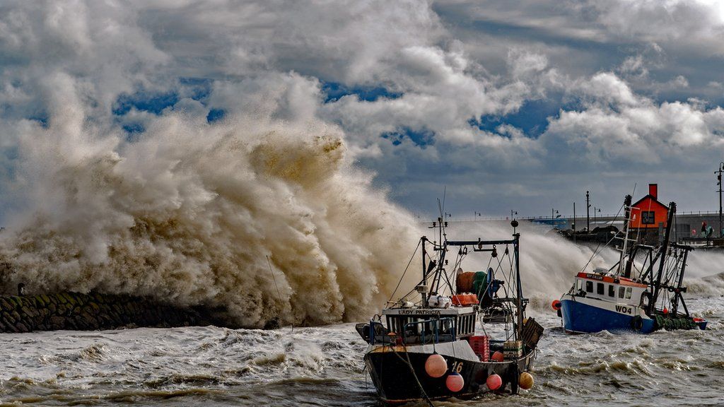 Fishing trawlers in the sea as waves crash against the harbour wall during Storm Ciaran in Folkestone, Kent.
