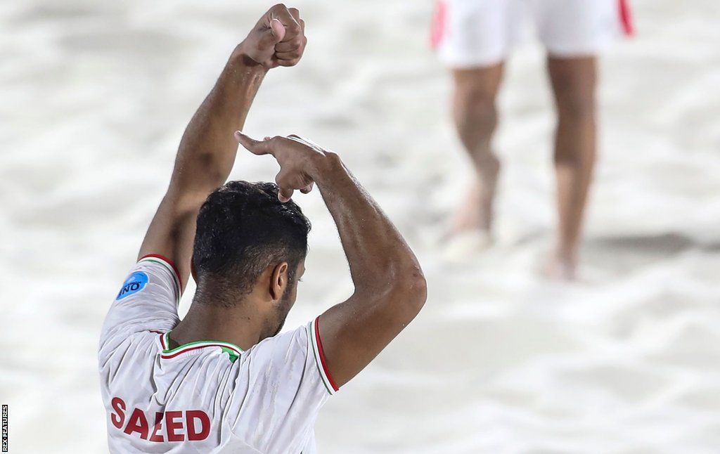 Iranian beach football player Saeed Piramoon pretends to cut his hair