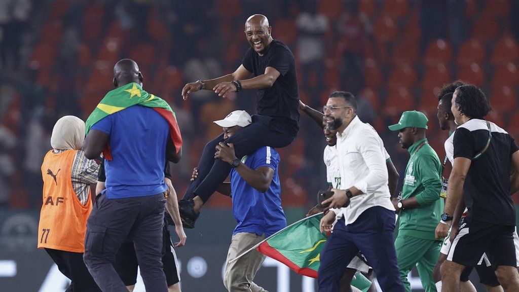 A member of Mauritania's coaching staff carries Amir Abdou on his shoulders