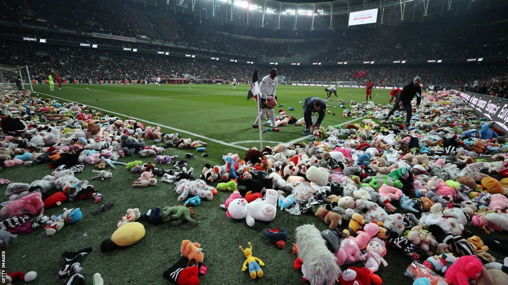 Players clear the pitch after Besiktas throw Teddy bears onto the field in support for the earthquake victim children