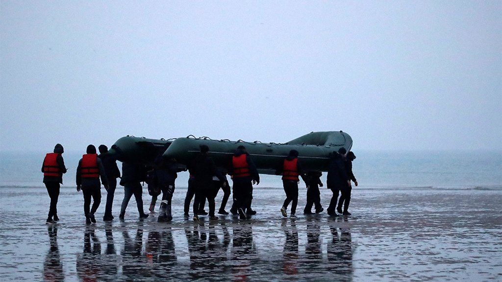 40 migrants run on the beach with an inflatable dinghy, near Wimereux, France, 24 November 2021
